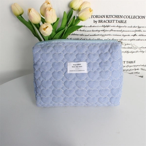 Close-up of quilted heart patterns on blue striped makeup bag with tulip decor