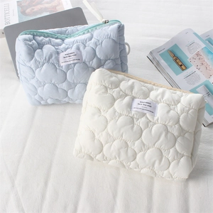 Detail of heart quilted cosmetic bags in light blue and beige with zipper closure