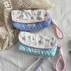 Detailed close-up of blue heart quilted pouch with floral flap and pink pom-pom trim