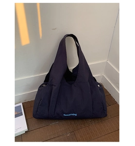 Detail view of navy blue nylon tote bag showing wide shoulder strap and printed logo