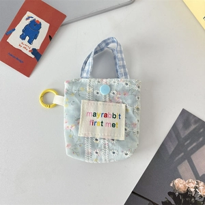 Détail d'une mini pochette florale avec broderie, poignée à carreaux et crochet jaune