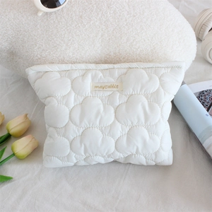 Detailed view of white quilted cloud makeup bag with mayrabbit logo on aesthetic background