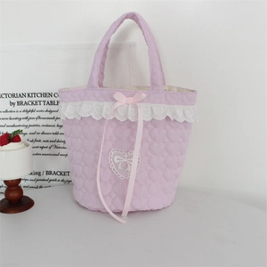 Close-up of quilted fabric bucket bag with lace edges and a pink ribbon bow detail