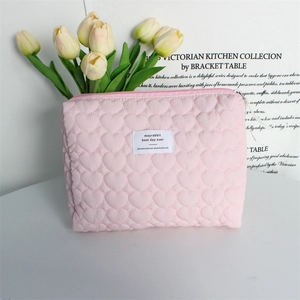 Detailed view of pink heart-quilted texture and brand label on a soft vanity bag