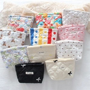 Flat lay of multiple quilted cotton cosmetic bags with floral, bear, and heart patterns