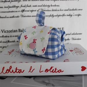 Detailed view of a mini checkered pouch with a bow-print flap and pink button closure