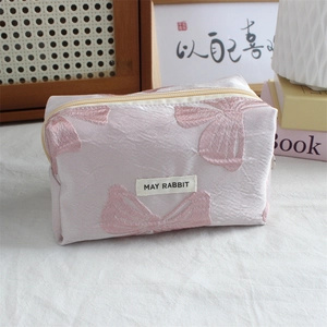 Detailed view of pink floral jacquard cosmetic bag with bow patterns and zipper closure