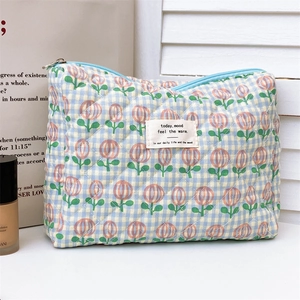 Detailed macro view of quilted tulip patterns and woven label on a blue plaid makeup bag