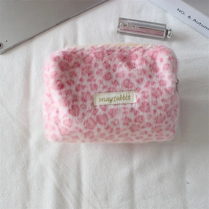 Dettaglio della borsa cosmetica in peluche leopardata rosa con etichetta ricamata oro