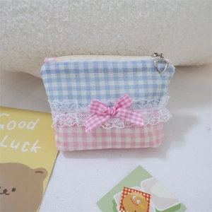 Detail of lace bow on blue and pink checkered cosmetic bag with heart zipper