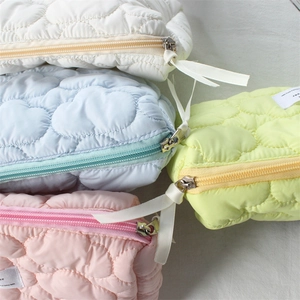 Close-up of heart-quilted texture and silk ribbon zipper pull on colorful cosmetic bags