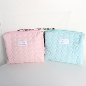 Detail of pink and blue quilted cosmetic bags with heart-shaped textures and zippers