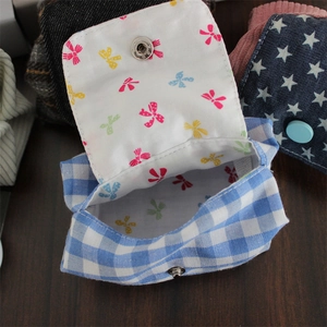 Close-up of blue plaid mini coin purse showing colorful bow print lining and metal snap