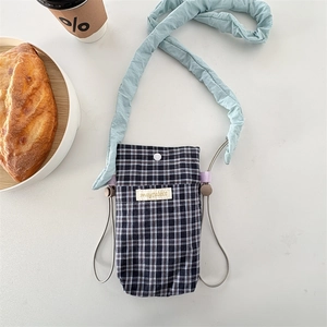 Macro shot of plaid mini crossbody bag with a blue ruffled strap on a cafe table