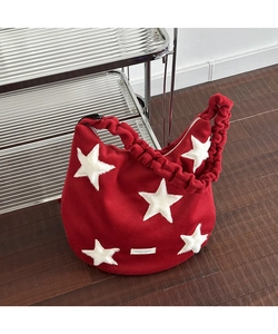 Macro shot of red wool tote bag featuring plush white stars and ruffled shoulder strap detail