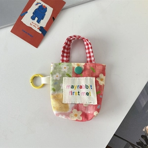 Détail d'une mini pochette florale avec poignée à carreaux rouges et crochet en plastique