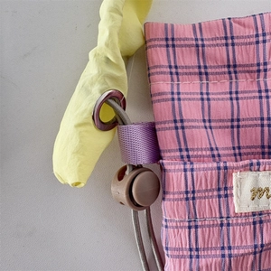 Detail of pink and blue checkered fabric bag with yellow drawstring and spring cord lock
