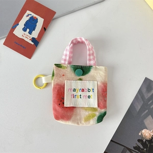 Détail d'une pochette pour écouteurs en tissu floral avec bouton et crochet de voyage