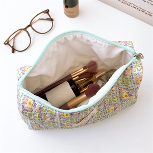 Macro view of large floral quilted pouch showing mint zipper and cosmetics storage interior