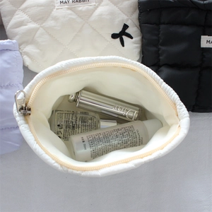 Quilted makeup bag detail showing spacious interior with zipper and bow accent