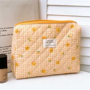 Close-up of quilted floral makeup bag with cherry patterns and yellow zipper