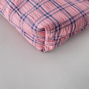Close-up of pink and blue checkered seersucker fabric with quilted texture on mini bag
