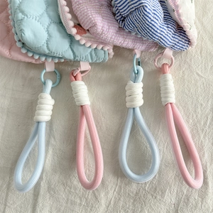 Detailed view of floral quilted pouch with pom-pom trim and rope zipper handle strap