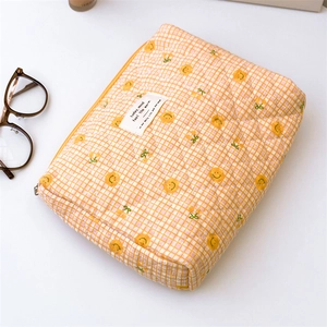Detail of yellow checkered quilted pouch with cherry patterns and metal zipper