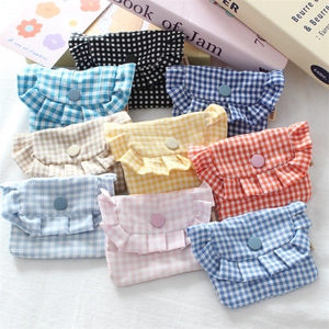 Detail of plaid mini pouches with ruffle edges and resin snap buttons in various colors