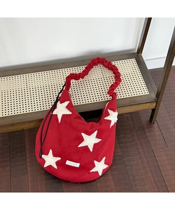 Detail of red wool shoulder bag featuring white star patch and ruffled strap design