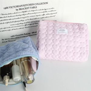 Detailed view of pink heart quilted cosmetic bag and blue striped pouch for toiletries