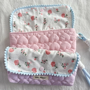 Detailed view of quilted cotton pouch with floral lining and mini pompom trim
