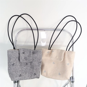 Detail of canvas tote bags with bow embroidery, flip cover and round buckle close-up