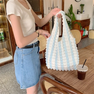 Close-up of blue and white striped bubble texture tote bag in a cozy cafe setting