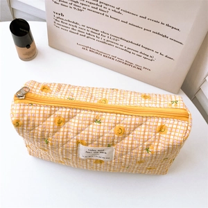 Detailed close-up of yellow checkered quilted cotton pouch with orange print and zipper