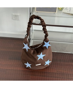 Detail of coffee brown wool tote bag featuring blue star patches and pleated handles