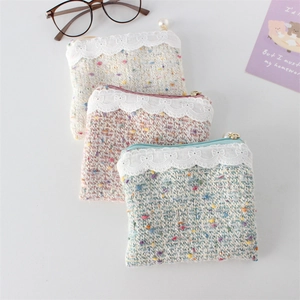 Detail of tweed coin purses with lace trim and pearl zipper pull in pastel colors