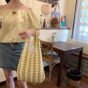 Close-up of yellow and white striped bubble textured fabric on a shoulder tote bag