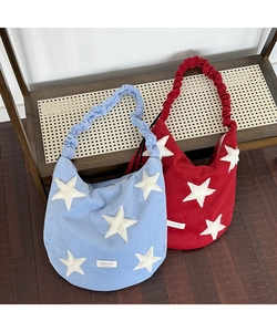 Detailed shot of two wool tote bags in red and blue with plush star patches and scrunchie straps