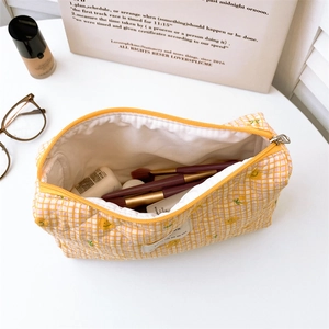 Macro detail of quilted checkerboard makeup bag with delicate floral and cherry embroidery