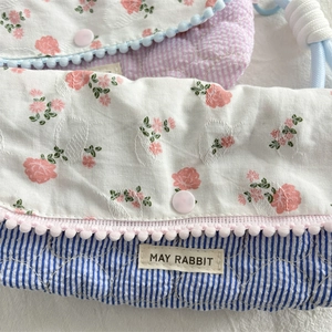 Close-up of quilted floral pencil case with pom-pom trim and snap button detail