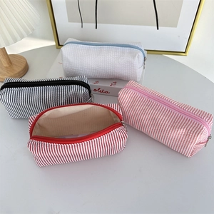 Detail of seersucker pencil cases showing striped textures and spacious zipper openings