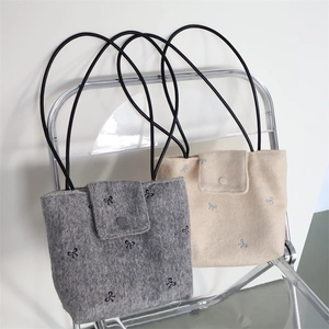 Detail of embroidered bow patterns on textured canvas tote bags with snap closure