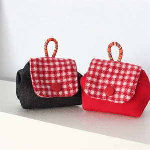 Mini denim and red fabric coin purses with red plaid flap and woven handles on white base