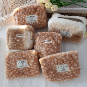 Detail of plush fawn print cosmetic bag featuring soft faux fur texture and brand label