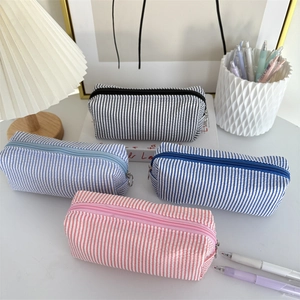 Minimalist seersucker striped pencil cases in four pastel colors on a stylish desktop