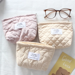 Macro view of quilted cotton pouches featuring floral and heart patterns with zippers