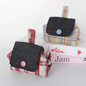Cute plaid canvas headphone pouches with denim lids and decorative buttons on prop books