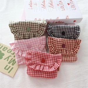Detailed view of mini checkered fabric coin pouches with ruffled edges and button closure