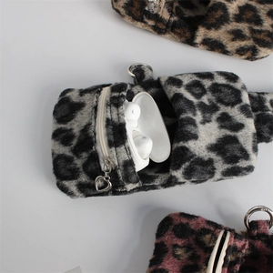 Macro shot of leopard plush pouches with heart-shaped zippers and metal hooks